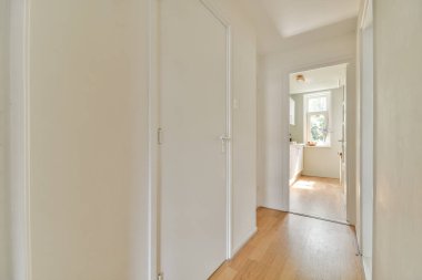 Beyaz duvarları ve aynalı gardırobu ve minimalist tarzda parke zemini olan boş dar koridor manzarası.