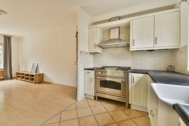 Geniş ışıklı mutfak, modern beyaz mobilyalar ve hafif dairede pop sanat portresi.