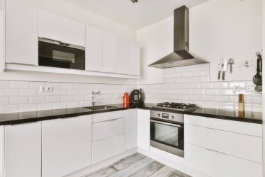 Konforlu kanepe döşenmiş oturma odasının rahat iç tasarımı ve modern tavan arası dairesinin beyaz duvarları ve sütunlarıyla döşenmiş ahşap masa.