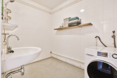 Sinks with mirrors and washing machine with shower box with glass door in modern bathroom with white tiled walls