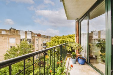 Narrow brick balcony with metal railings, wooden chair and door