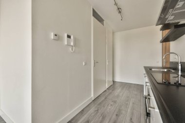 Koridoru ve ahşap parke zemini olan boş beyaz mutfağın içi.