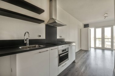 Pencereleri ve ahşap parke zemini olan boş beyaz mutfağın içi.