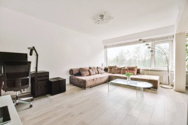 Yastıkları olan rahat bir kanepe. Duvara yaslanmış TV ve dekorasyonlar modern sevgi odasında.