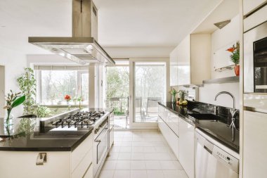 Stüdyo dairesinin modern minimalist tarzı iç tasarımı açık beyaz mutfak ve yemek masası ve sandalyeleri tavan arası lambasıyla aydınlatılmış.