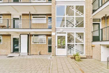 Levhalı, kaldırımlı ve ahşap kapılı bir binanın ön manzarası daireye çıkıyor.