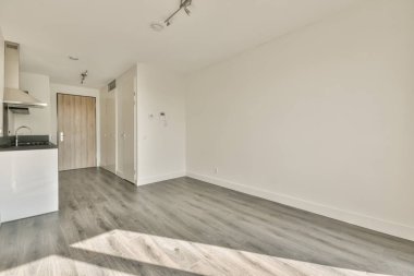 Pencereleri ve ahşap parke zemini olan boş beyaz mutfağın içi.