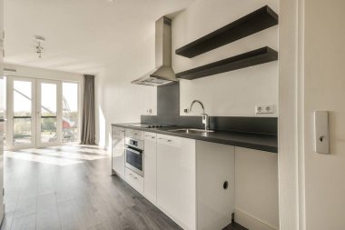 Pencereleri ve ahşap parke zemini olan boş beyaz mutfağın içi.