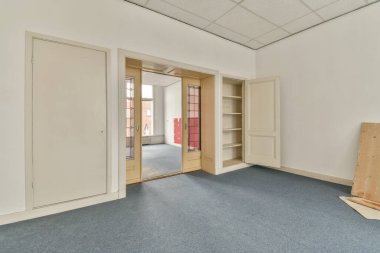 Büyük balkon pencereli, perdeli ve ahşap parke zeminli boş beyaz odanın içi.