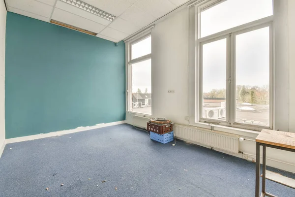 Büyük balkon pencereli, perdeli ve ahşap parke zeminli boş beyaz odanın içi.