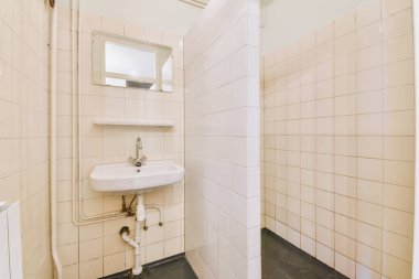 Evdeki çağdaş tuvaletteki aynanın altındaki duvarda musluk ve sıvı sabun asılı.