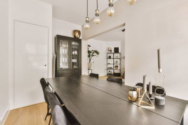 Contemporary minimalist style interior design of light studio apartment with wooden table and chairs in dining zone in living room with white walls and parquet floor