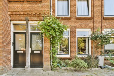 Levhalı, kaldırımlı ve ahşap kapılı bir binanın ön manzarası daireye çıkıyor.