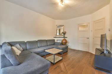 Şık bir oturma odası, rahat bir kanepe ve modern bir dairede masanın etrafına yerleştirilmiş yastıklı koltuklar.