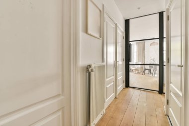 Çağdaş dairenin geniş odasındaki dinlenme odası ve mutfağın yakınındaki sandalyeli ve çiçekli masa.