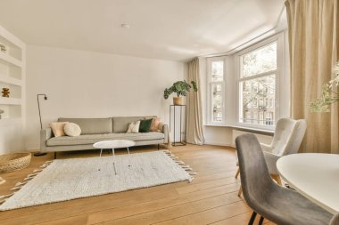 Çağdaş dairenin geniş odasındaki dinlenme odası ve mutfağın yakınındaki sandalyeli ve çiçekli masa.