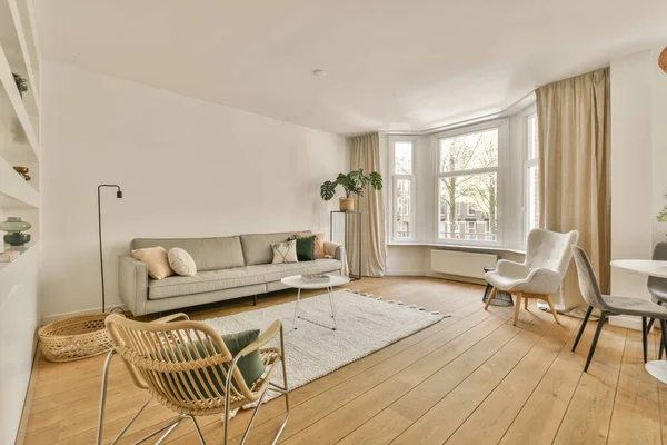 Çağdaş dairenin geniş odasındaki dinlenme odası ve mutfağın yakınındaki sandalyeli ve çiçekli masa.