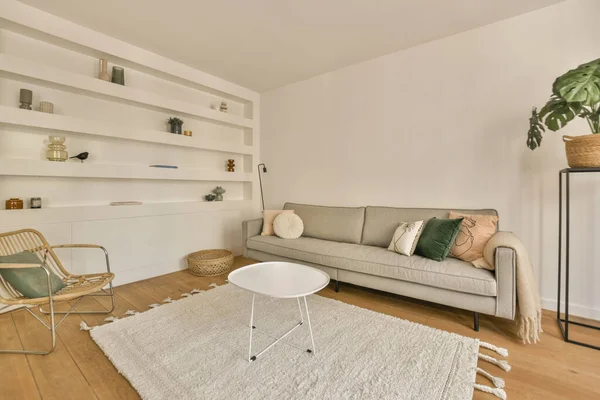 Çağdaş dairenin geniş odasındaki dinlenme odası ve mutfağın yakınındaki sandalyeli ve çiçekli masa.