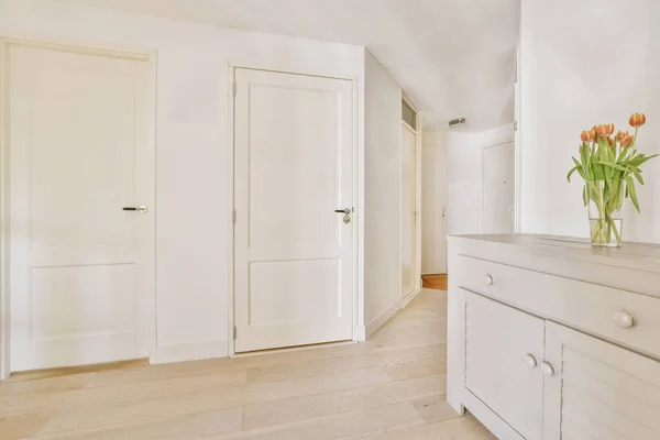 Light narrow hallway with many doors in white walls and glowing lamp over lumber floor