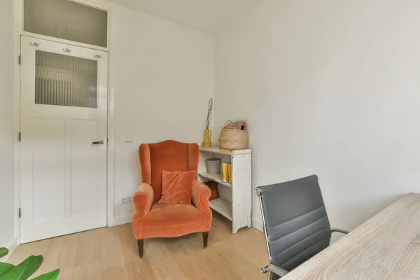 Minimalist interior of study room with parquet floor and white walls furnished with settee and table with shelf rack