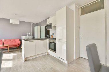 Çağdaş dairenin geniş odasındaki dinlenme odası ve mutfağın yakınındaki sandalyeli ve çiçekli masa.