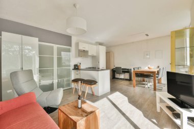 Çağdaş dairenin geniş odasındaki dinlenme odası ve mutfağın yakınındaki sandalyeli ve çiçekli masa.