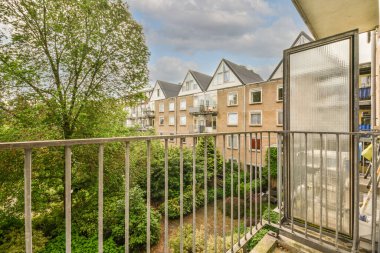 Panoramic view of brick buildings with parking and trees from small balcony