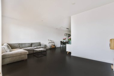 Günümüz minimalist tasarımı. Hafif stüdyo dairesinin ahşap masası ve oturma odası ile beyaz duvarları ve parke zemini arasında yemek masası ve sandalyeleri var.