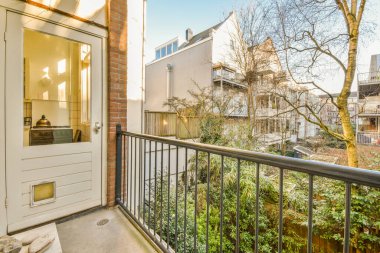 Eski tuğla binaların panoramik manzarası. Küçük balkondan park yerleri ve ağaçlar.