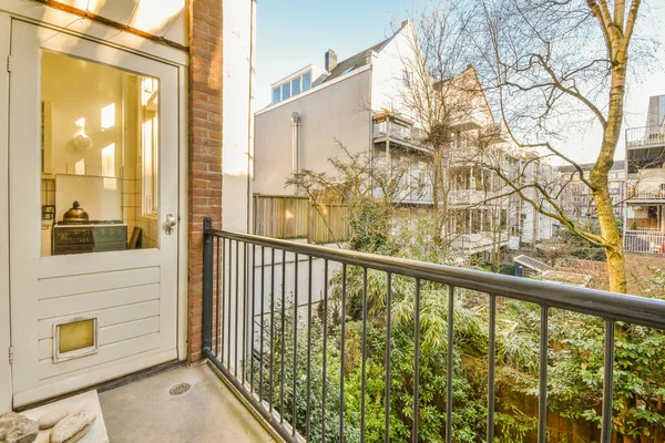 Eski tuğla binaların panoramik manzarası. Küçük balkondan park yerleri ve ağaçlar.