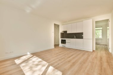 Pencereleri ve ahşap parke zemini olan boş beyaz mutfağın içi.