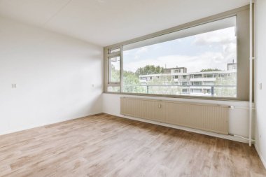 Evdeki boş ışık odasında, beyaz duvardaki plastik pencere ve radyatör.