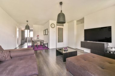 Modern apartmandaki dekorasyonlu ve televizyonlu, rahat koltuğun yanına yerleştirilmiş eski püskü ahşap masa.