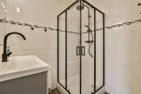 壁ハングトイレと白いタイル張りのバスルームでシンクベースキャビネットとミラーキャビネット — ストック写真