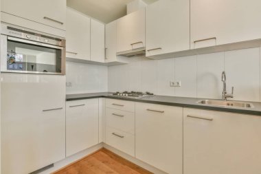 Çağdaş açık mutfak, yemek masası seti ve ferah odada gri kanepe.