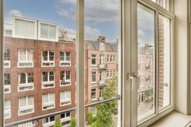 Büyük balkon pencereli, perdeli ve ahşap parke zeminli boş beyaz odanın içi.