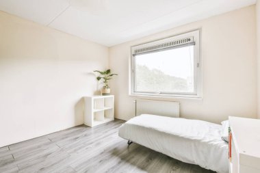 Yatak odasının iç tasarımı, yatak odası ve ahşap gardırop modern dairenin penceresinin kenarına yerleştirilmiş.