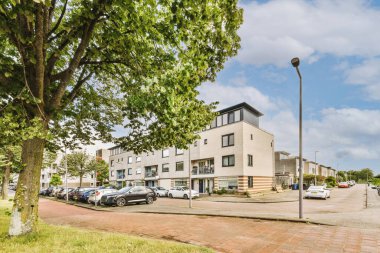 Arabaları, ağaçları ve fenerleri olan boş bir kaldırımdan panorama manzaralı evler.
