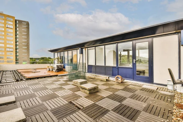 Bright brick balcony with metal railings, wooden chair and door with glass leads to the kitchen