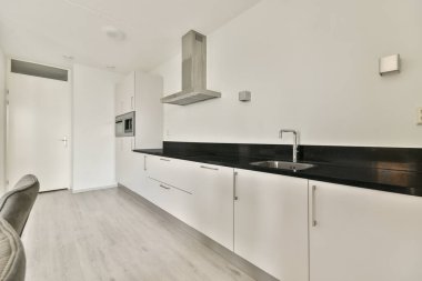 Çağdaş dairenin geniş odasındaki dinlenme odası ve mutfağın yakınındaki sandalyeli ve çiçekli masa.