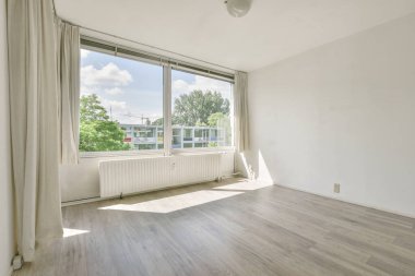 Evdeki boş ışık odasında, beyaz duvardaki plastik pencere ve radyatör.