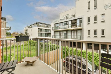 Front view of buildings and cars with bicycles from small balcony with railings