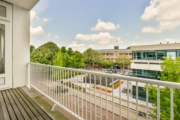Front view of buildings and cars from small balcony with railings