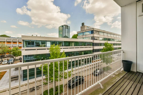 Front view of buildings and cars from small balcony with railings