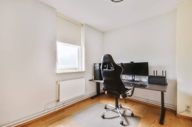 Modern apartmandaki hafif iş yerinde bilgisayar monitörleri ve beyaz tahtanın olduğu masanın yanına konforlu sandalye