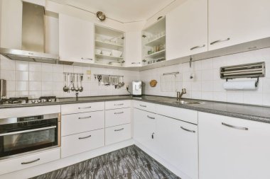 Minimalist tarzı beyaz mobilyalı, lavabolu ve sobalı bir ev mutfağı.