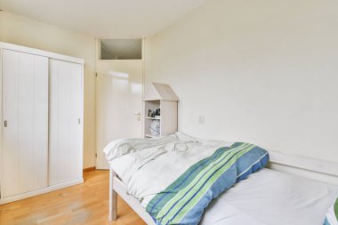 Yatak odasının iç tasarımı, yatak odası ve ahşap gardırop modern dairenin penceresinin kenarına yerleştirilmiş.