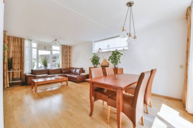 Günümüz minimalist tasarımı. Hafif stüdyo dairesinin ahşap masası ve oturma odası ile beyaz duvarları ve parke zemini arasında yemek masası ve sandalyeleri var.