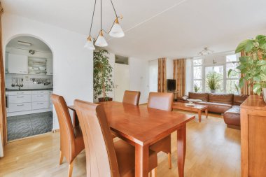 Günümüz minimalist tasarımı. Hafif stüdyo dairesinin ahşap masası ve oturma odası ile beyaz duvarları ve parke zemini arasında yemek masası ve sandalyeleri var.