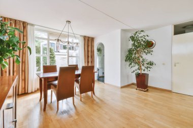 Günümüz minimalist tasarımı. Hafif stüdyo dairesinin ahşap masası ve oturma odası ile beyaz duvarları ve parke zemini arasında yemek masası ve sandalyeleri var.